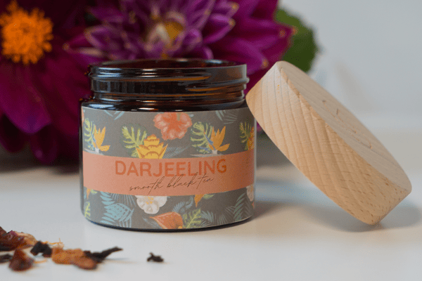 Pharmacos Tiegel_Holzdeckel mit Schwarztee Team vor Bergkulisse